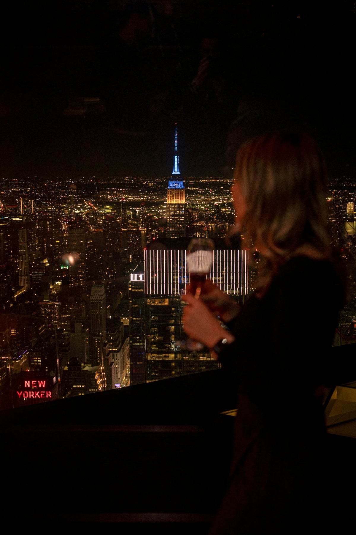 Woman with a drink above the New York skyline at night