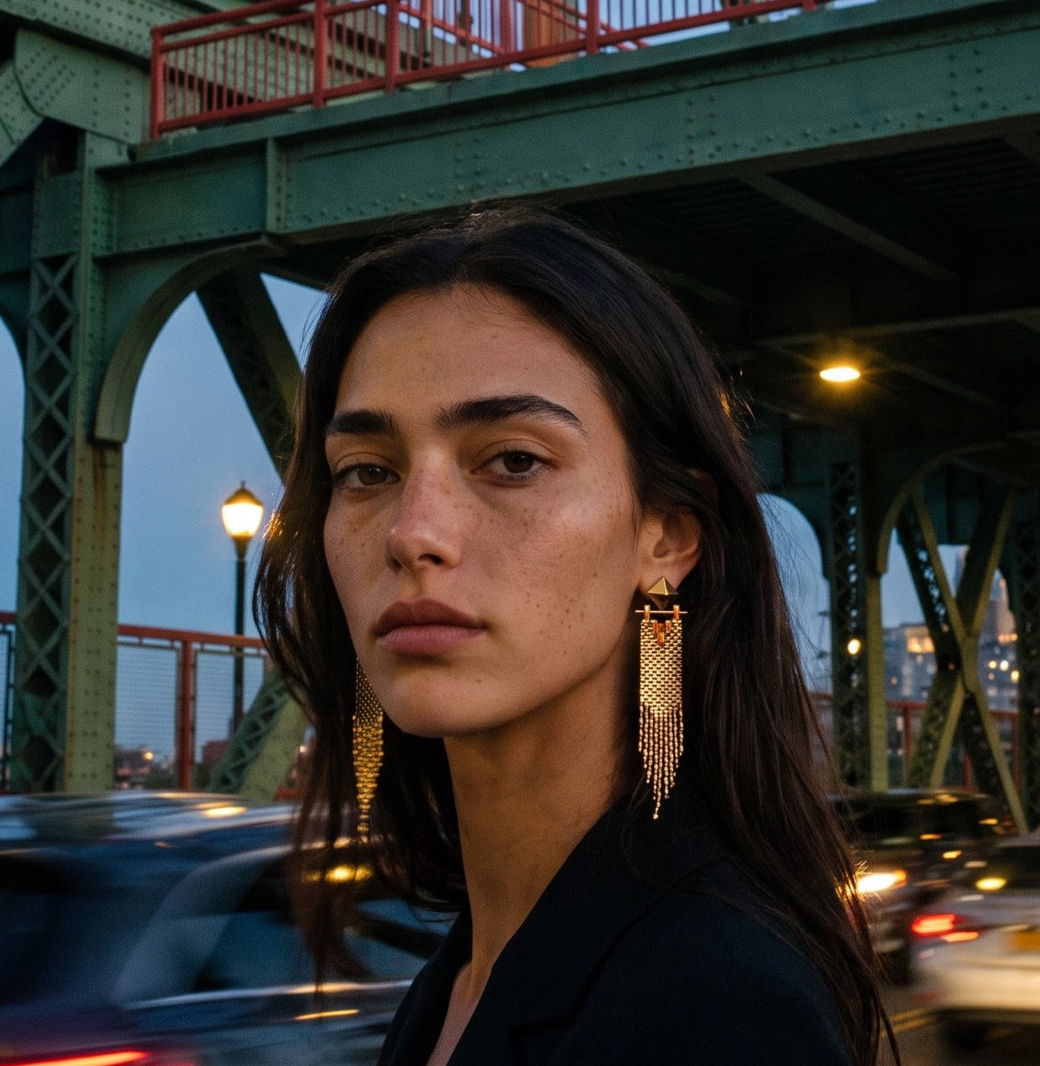 Woman wearing Amante gold fringe earrings on a New York bridge at dusk